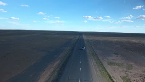 Aerial-drone-shot-following-a-van-on-a-deserted-road-in-mongolia